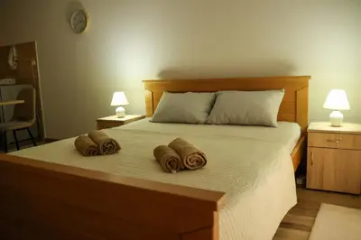 a bed with two towels on it with two lamps at Apartman San in Ruma