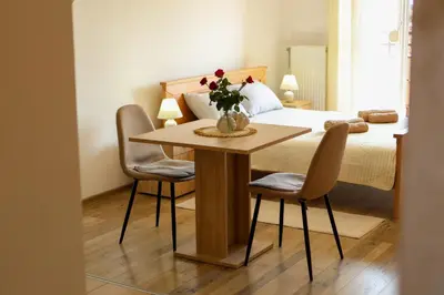 a bedroom with a table with chairs and a bed at Apartman San in Ruma