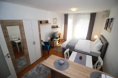 a small room with a bed and a desk with a table at Apartman Bizmark in Novi Beograd