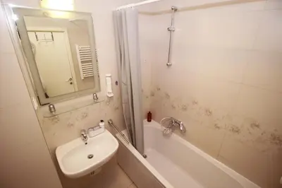 a bathroom with a sink and a tub and a mirror at Apartman Bizmark in Novi Beograd