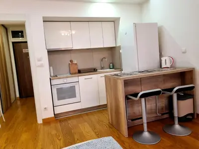 a kitchen with white cabinets and a counter with stools at Urban studio in Bežanija