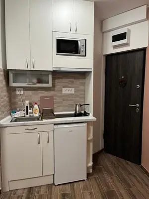 a kitchen with white cabinets and a black door at Squeeze The Day in Belgrade