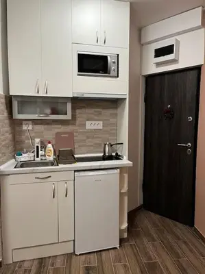 a kitchen with white cabinets and a black door at Squeeze The Day in Belgrade