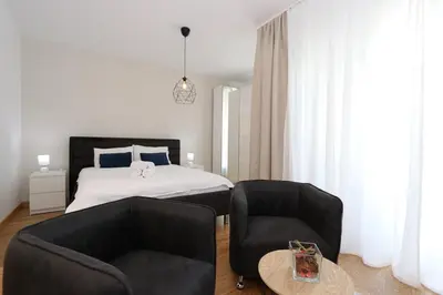 a bedroom with a bed and two chairs and a table at Savada BLUE - apartman na Novom Beogradu sa parkingom doplata 5 evra dan in Belgrade