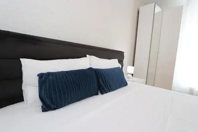 a white bed with two blue pillows on it at Savada BLUE - apartman na Novom Beogradu sa parkingom doplata 5 evra dan in Belgrade
