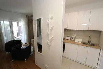 a kitchen with white cabinets and a chair in a room at Savada BLUE - apartman na Novom Beogradu sa parkingom doplata 5 evra dan in Belgrade