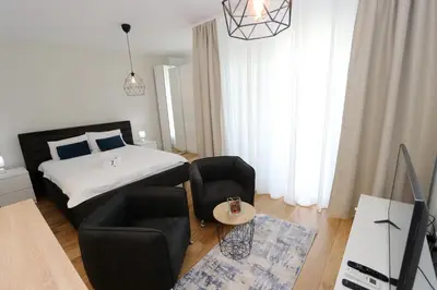 a bedroom with a bed and two chairs and a table at Savada BLUE - apartman na Novom Beogradu sa parkingom doplata 5 evra dan in Belgrade