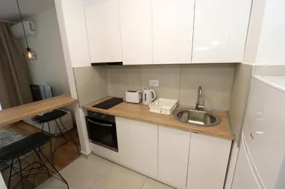 a small kitchen with white cabinets and a sink at Savada BLUE - apartman na Novom Beogradu sa parkingom doplata 5 evra dan in Belgrade