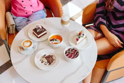 a woman sitting at a table with a plate of desserts at Hotel Balkan in Belgrade