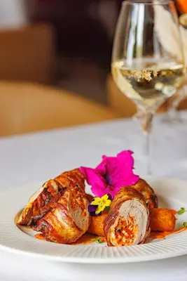 a white plate with a piece of food and a glass of wine at Hotel Balkan in Belgrade