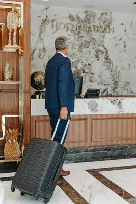 a man in a suit is pulling a suitcase at Hotel Balkan in Belgrade