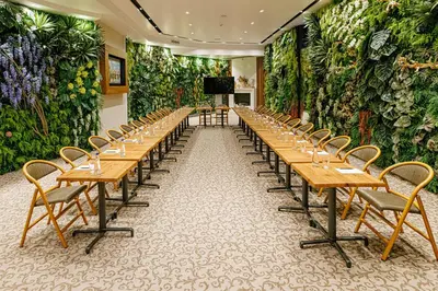 a long row of tables and chairs in a room with plants at Hotel Balkan in Belgrade
