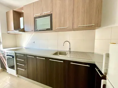 a kitchen with wooden cabinets and a sink at Modesti - stan na dan Novi Beograd sa parkingom 5 evra po danu in Belgrade