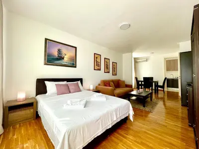 a bedroom with a large bed and a living room at Modesti - stan na dan Novi Beograd sa parkingom 5 evra po danu in Belgrade
