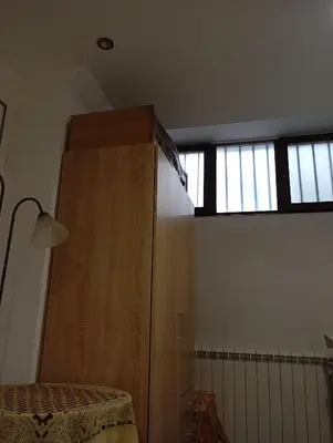 a bedroom with a wooden cabinet and two windows at Belgrade apartment deluxe in Belgrade