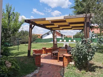 a wooden pergola with benches and tables in a yard at Big Borak in Veliki Borak
