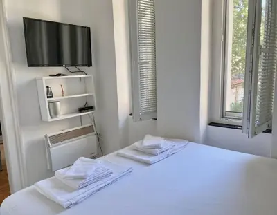 a white room with a bed with a tv on the wall at Square 29 in Belgrade