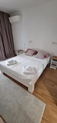 a large white bed in a room with wooden floors at Oaza 45 in Belgrade