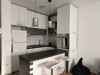 a kitchen with white cabinets and a black counter top at Miyaki Apartment in Belgrade