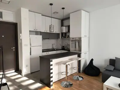 a kitchen with white cabinets and a black counter top at Miyaki Apartment in Belgrade