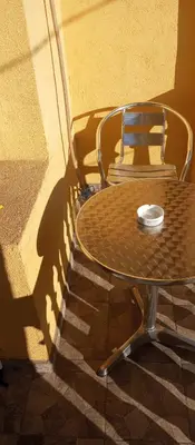 a table and chair in the shadows of a building at Airport MD rooms in Belgrade