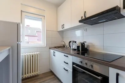 a kitchen with white cabinets and a stove top oven at Aurora Apartman in Belgrade
