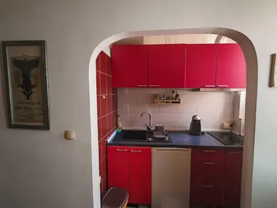 a red kitchen with a sink and red cabinets at Republic Square Studio in Belgrade