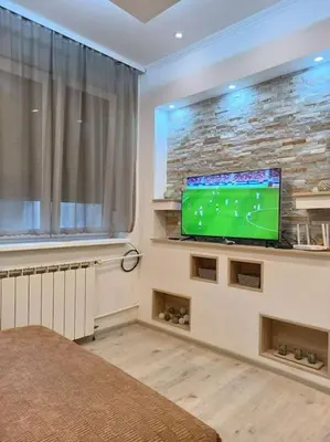 a living room with a flat screen tv on a stone wall at Bohemian Lux Apartment Skadarlija in Belgrade