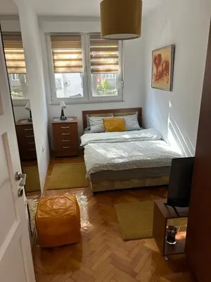 a small bedroom with a bed and two windows at Martina Lux in Belgrade