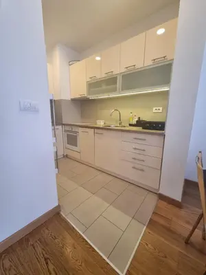 a kitchen with white cabinets and a tile floor at Grand Residence in Bežanija