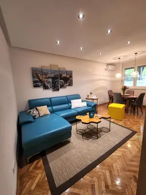 a living room with a blue couch and a table at Nancy's Cozy Business Apartment in Bežanija