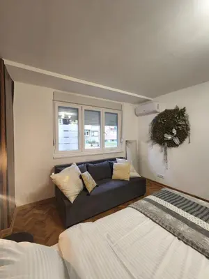 a living room with a couch and a bed at Nancy's Cozy Business Apartment in Bežanija