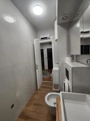 a white bathroom with a toilet and a sink at Nancy's Cozy Business Apartment in Bežanija