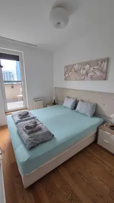 a bedroom with a bed with blue sheets and a window at Skyline in Belgrade