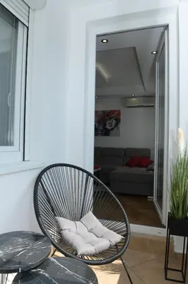 a rattan chair in a living room with a couch at Arena Lux in Novi Beograd