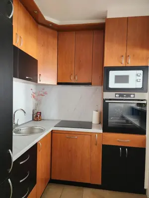 a small kitchen with wooden cabinets and a microwave at Arena Lux in Novi Beograd