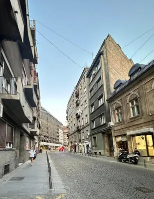 a woman walking down a cobblestone street with buildings at Cloud Downtown apartment in Belgrade