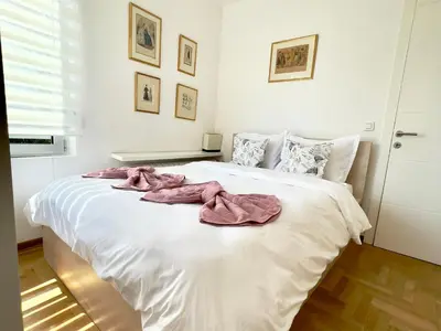 a bedroom with a white bed with pink towels on it at Regina Vracar apartment and garage in Vračar (historical)