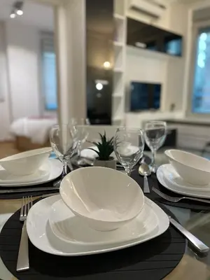 a table with white plates and wine glasses on it at Regina Vracar apartment and garage in Vračar (historical)