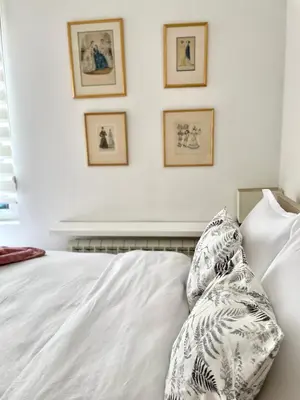 a white bed with pillows and framed pictures on the wall at Regina Vracar apartment and garage in Vračar (historical)