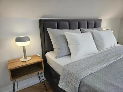 a bed with white pillows and a lamp on a night stand at Apartment LUMALU in Belgrade