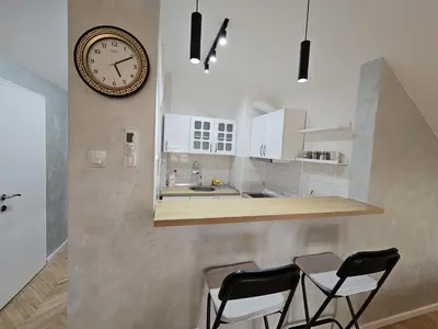 a kitchen with a clock on the wall and two chairs at Apartment LUMALU in Belgrade
