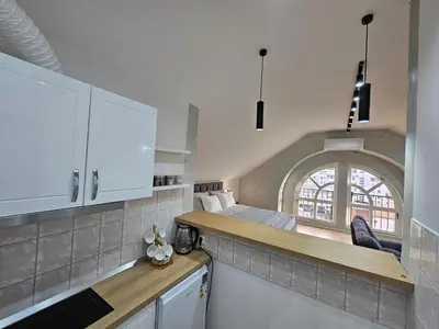 a kitchen with white cabinets and a bed in a room at Apartment LUMALU in Belgrade