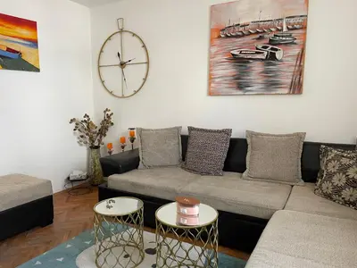 a living room with a couch and a clock on the wall at JOVAN APARTMAN in Rospi Ćuprija