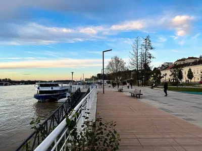 a boat is docked next to a sidewalk next to the water at Loft with Cinema & Foosball Sava View Old Town in Belgrade