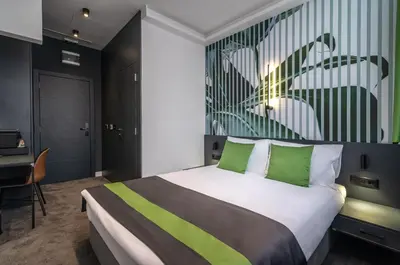 a bedroom with a bed with green pillows and a desk at City Joy - sports Center Tasmajdan in Belgrade