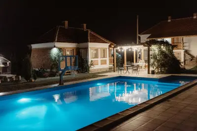 a swimming pool in front of a house at night at Uzivancija in Lazarevac