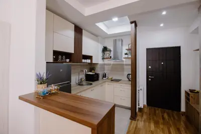 a kitchen with white cabinets and a wooden table at Cherry Lux Apartments in Arandjelovac
