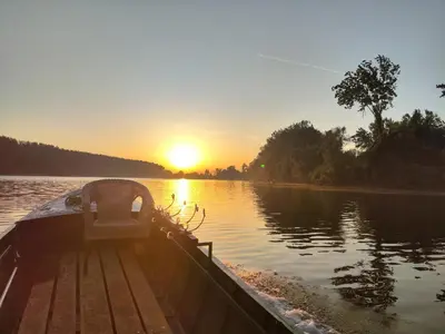 a boat on the water with the sunset in the background at Vikendica Tisa Dukatar in Titel