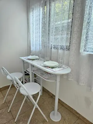 a white table with two chairs and a window at Booking Apartments Alone 2 in Zemun
